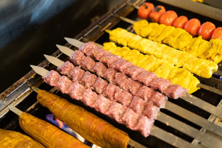 Koobideh and joojeh kabob skewers on the grill