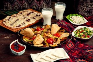 A family sharing a meal around a wooden table at a family-friendly Persian restaurant Woodland Hills location, featuring saffron rice, grilled kabob platters, flatbread, and yogurt dip.