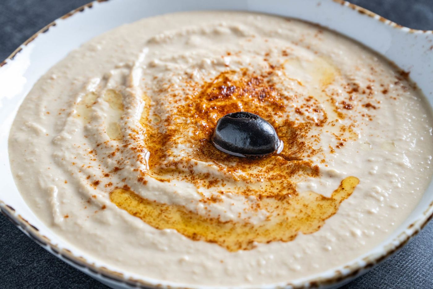 Creamy hummus with olive oil, paprika and a whole olive, served at Kabob Village