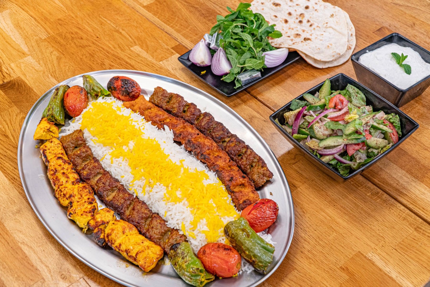 Mixed Kabob Village platter with saffron rice, beef and chicken kabob, grilled tomato, Shirazi salad and warm lavash